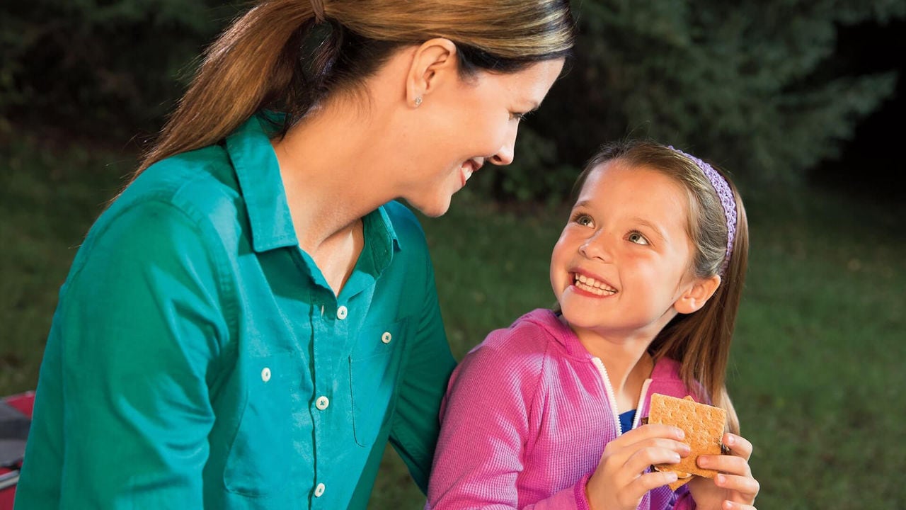 mother and daughter smiling while eating smores