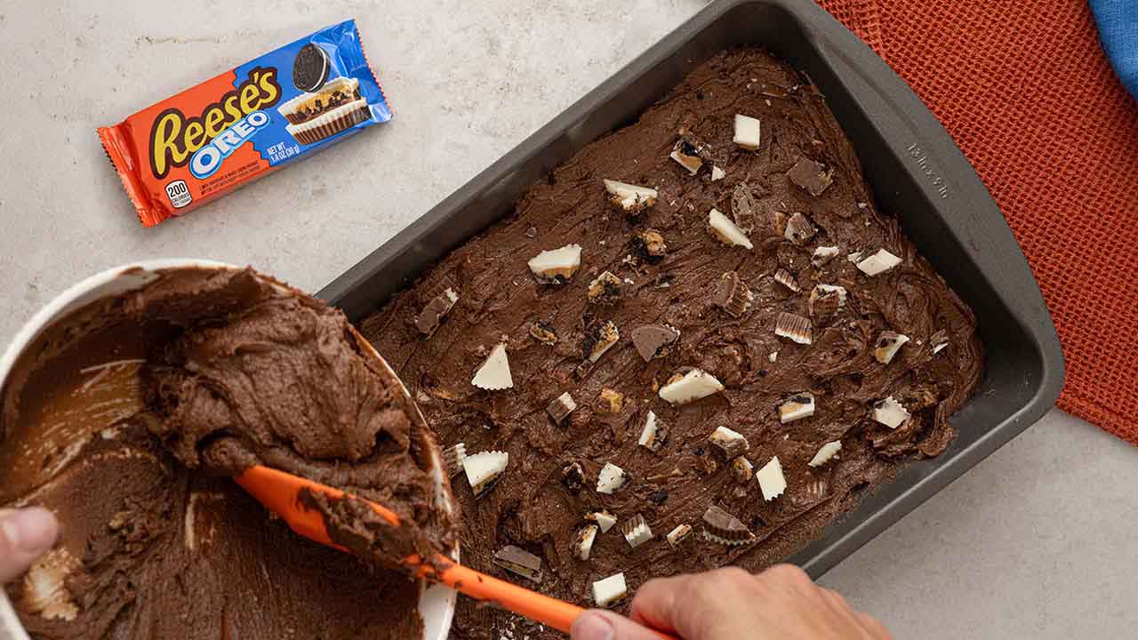 spreading brownie batter into the greased baking pan