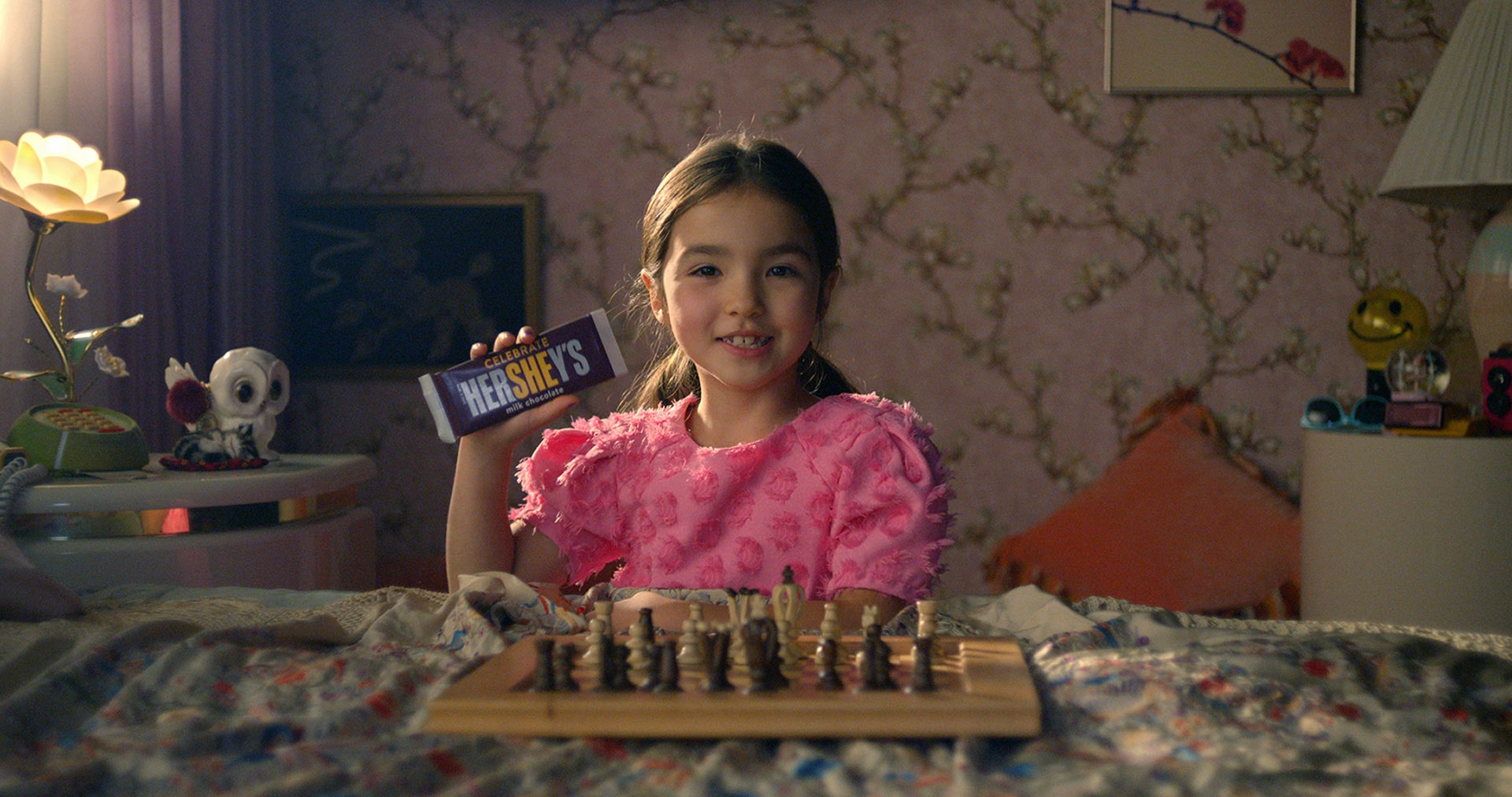 little girl holding hersheys celebrate she bar while playing chess