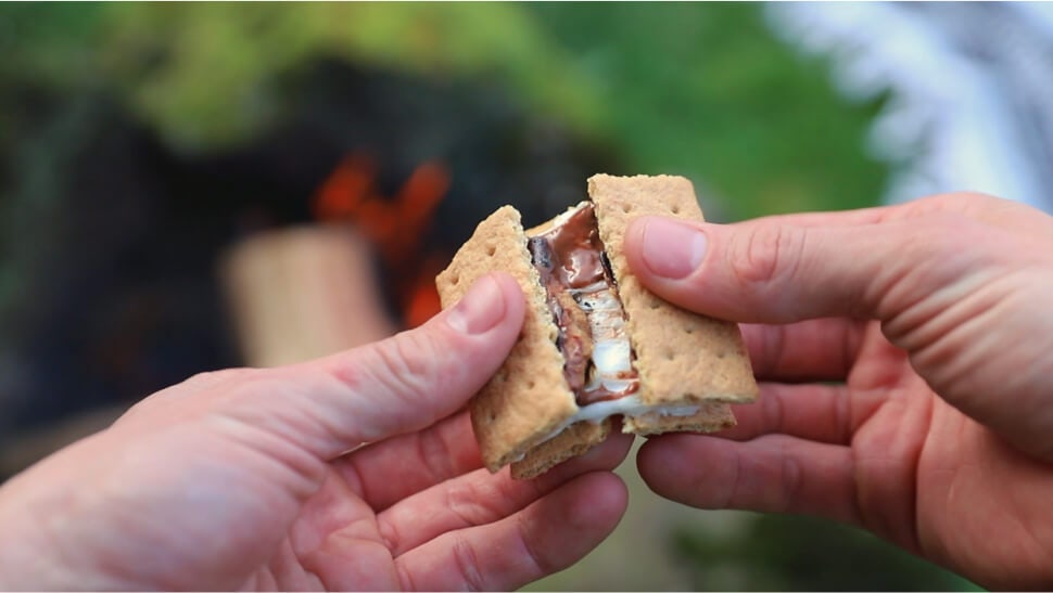 person breaking a classic flavored campfire smore in half