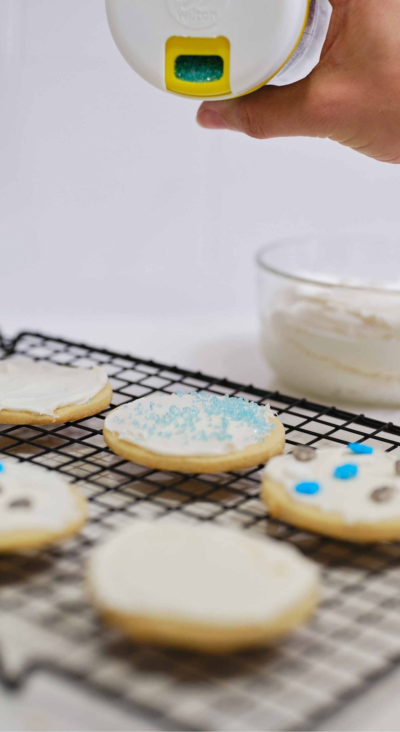 person decorating sugar cookies with assorted sprinkles