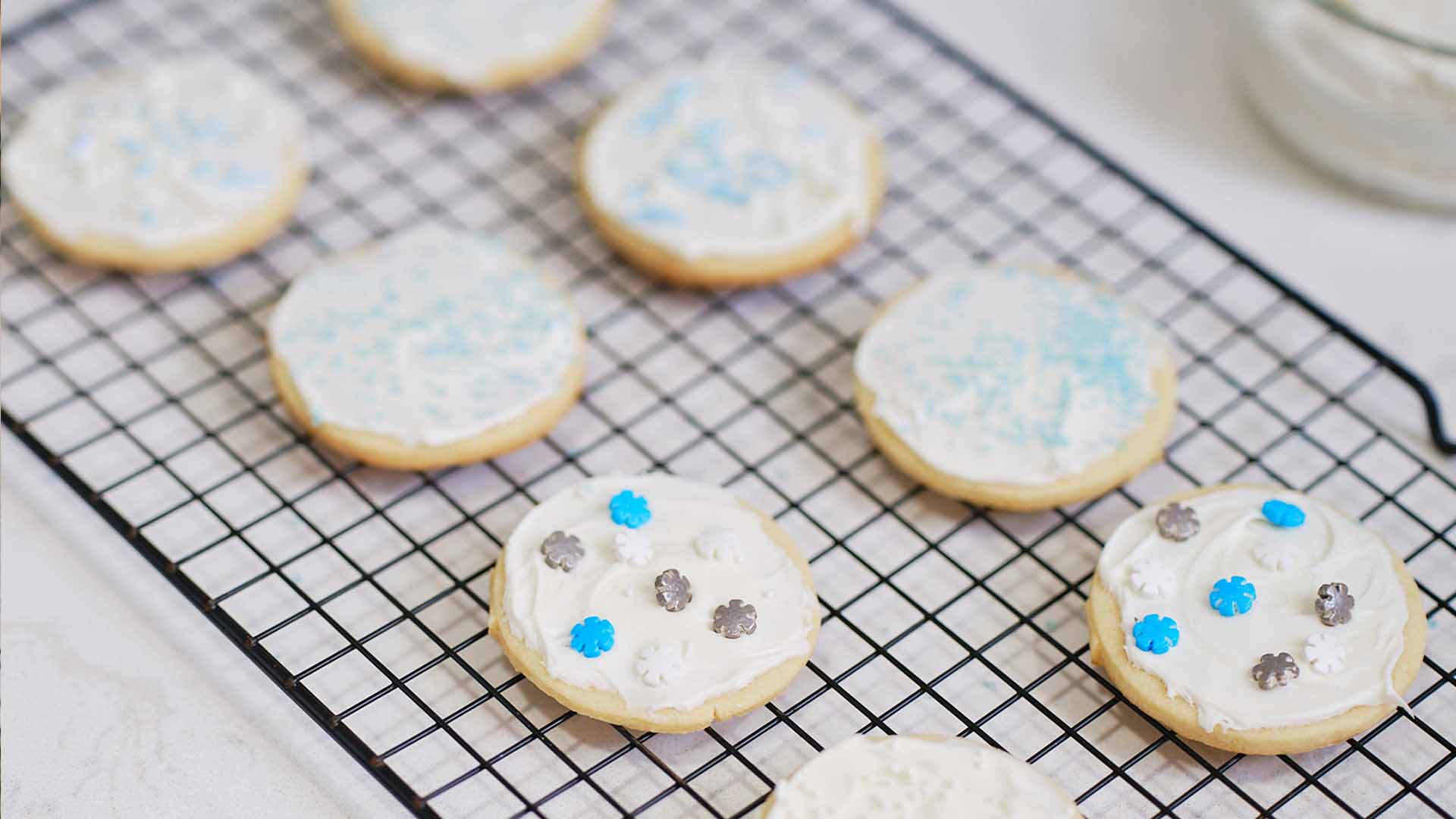 sugar cookies decorated with icing and sprinkles cooling on wire rack